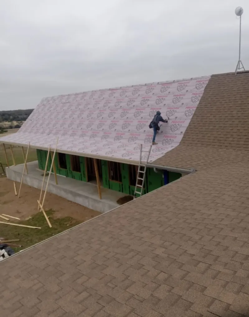 Worker preparing underlayment for a metal roof installation in Lochearn